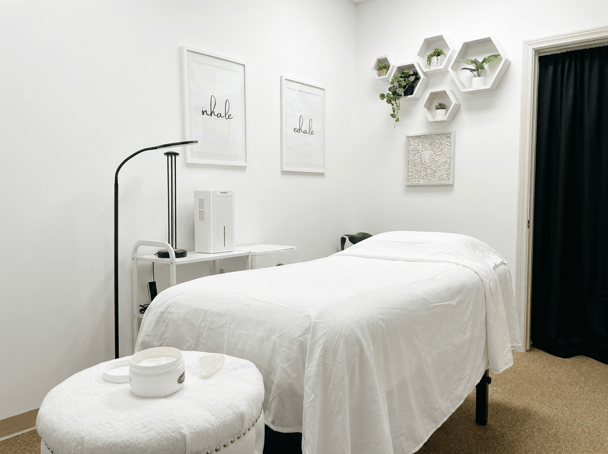 Calm, minimal treatment room with a linen-dressed table and greenery